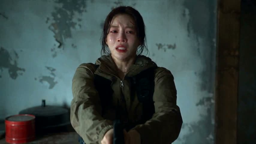 Original frame from zombie3: a dark-haired woman in an olive jacket in a worn blue-green room