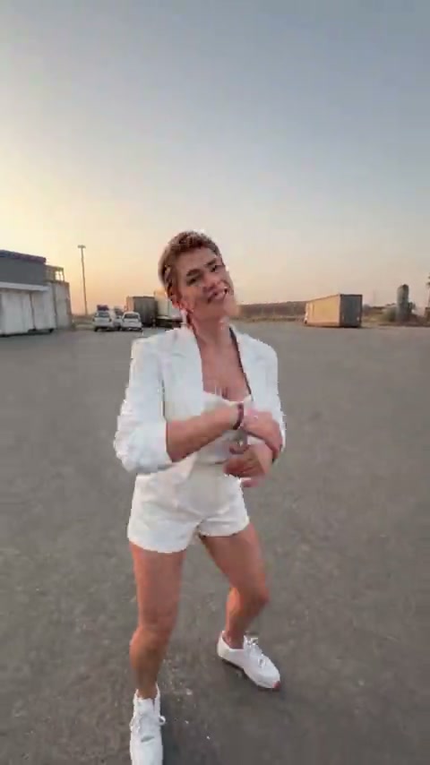 Original vertical video frame of the opening dancer in a white outfit on the forecourt