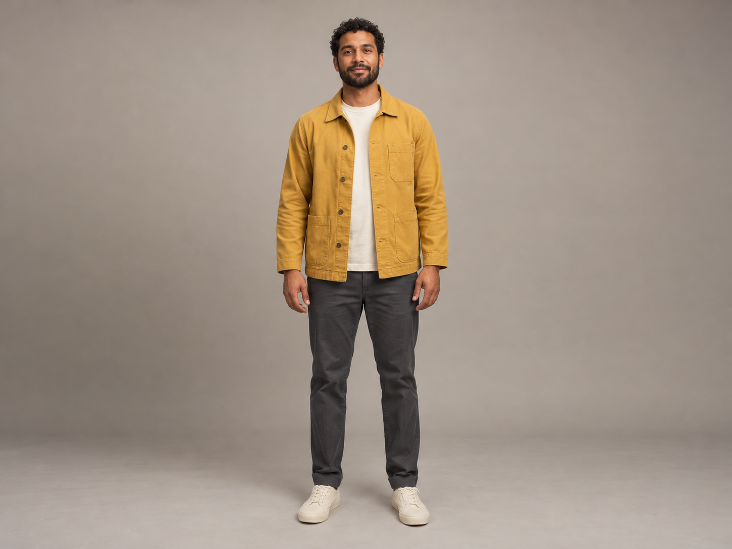 An original AI-generated adult man with curly hair, a mustard jacket and charcoal trousers